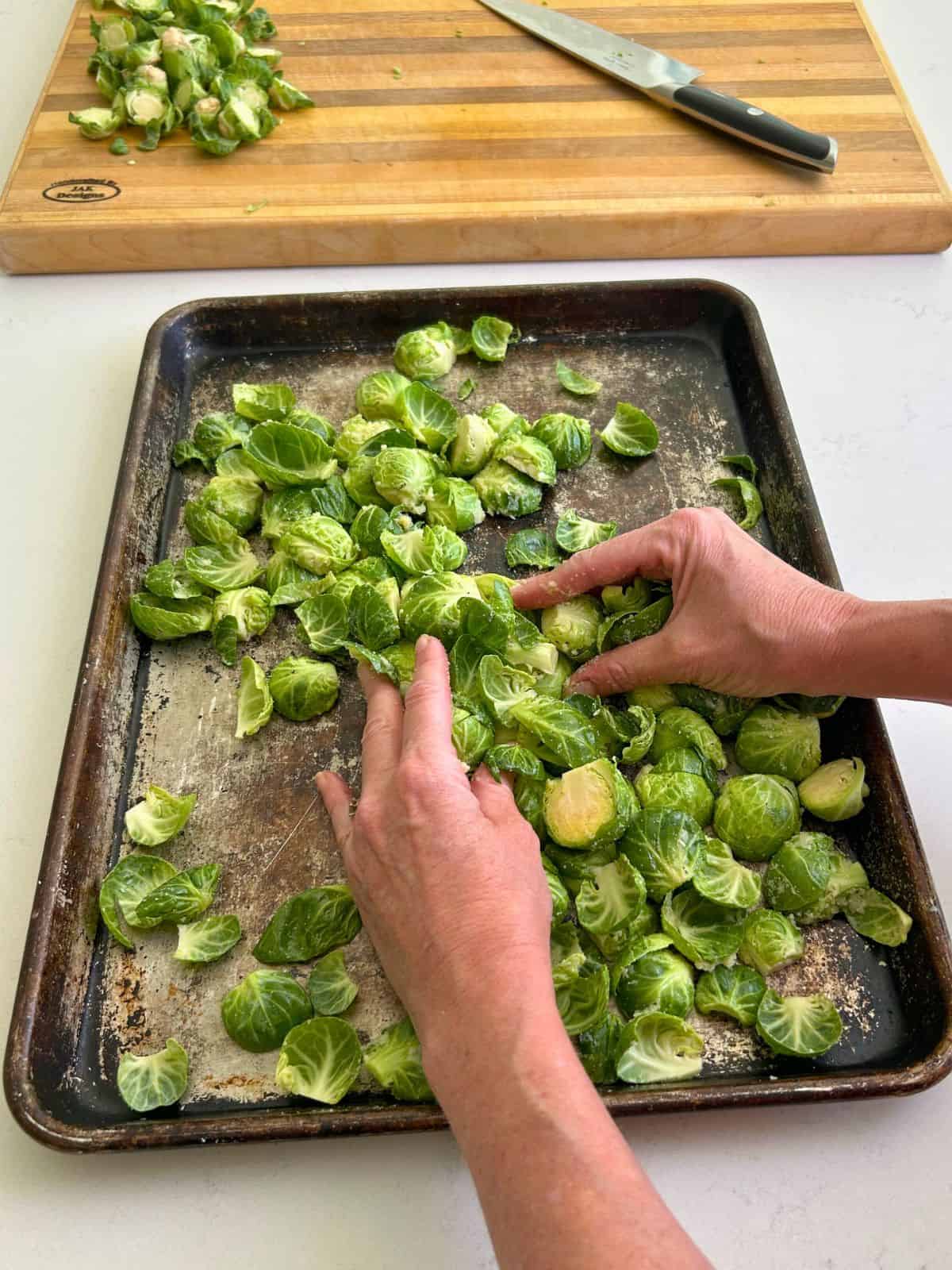 Hand massaging the ghee, salt, and pepper into the brussel sprouts directly on the sheet pan.