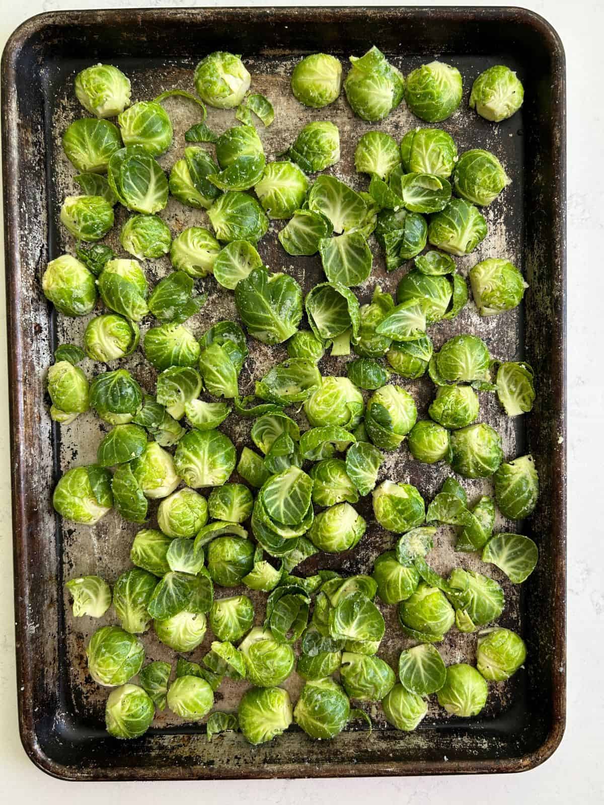 Brussel sprout halves spread out face down on cookie sheet.