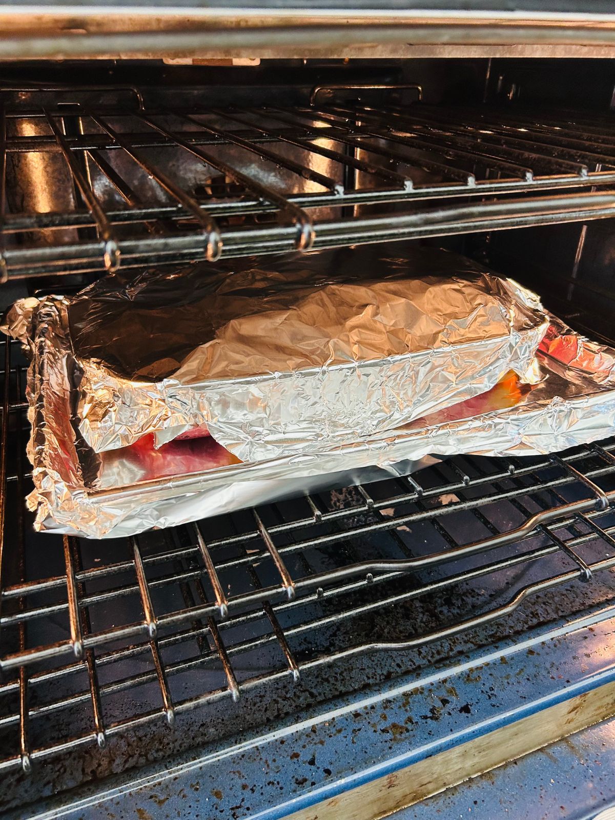 The casserole containing the pork pieces is wrapped in foil and on top of a foil lined cookie sheet in the center of the oven.