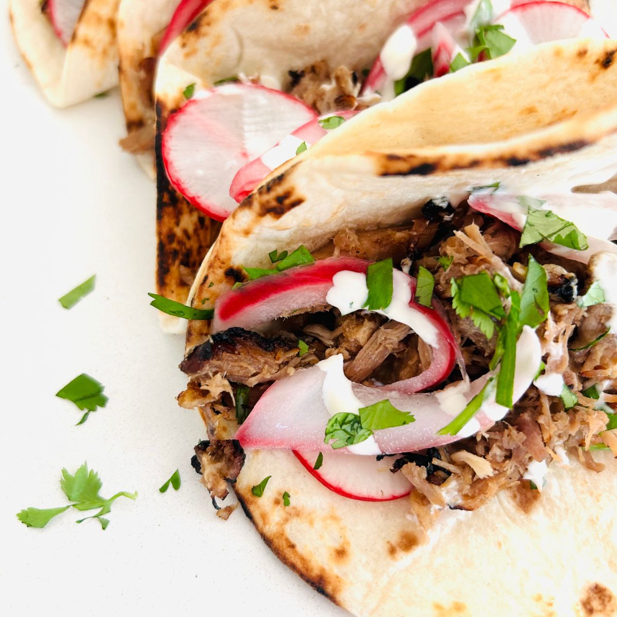 Pickled red onions on top of taco meat with chopped cilantro inside a flour tortilla.