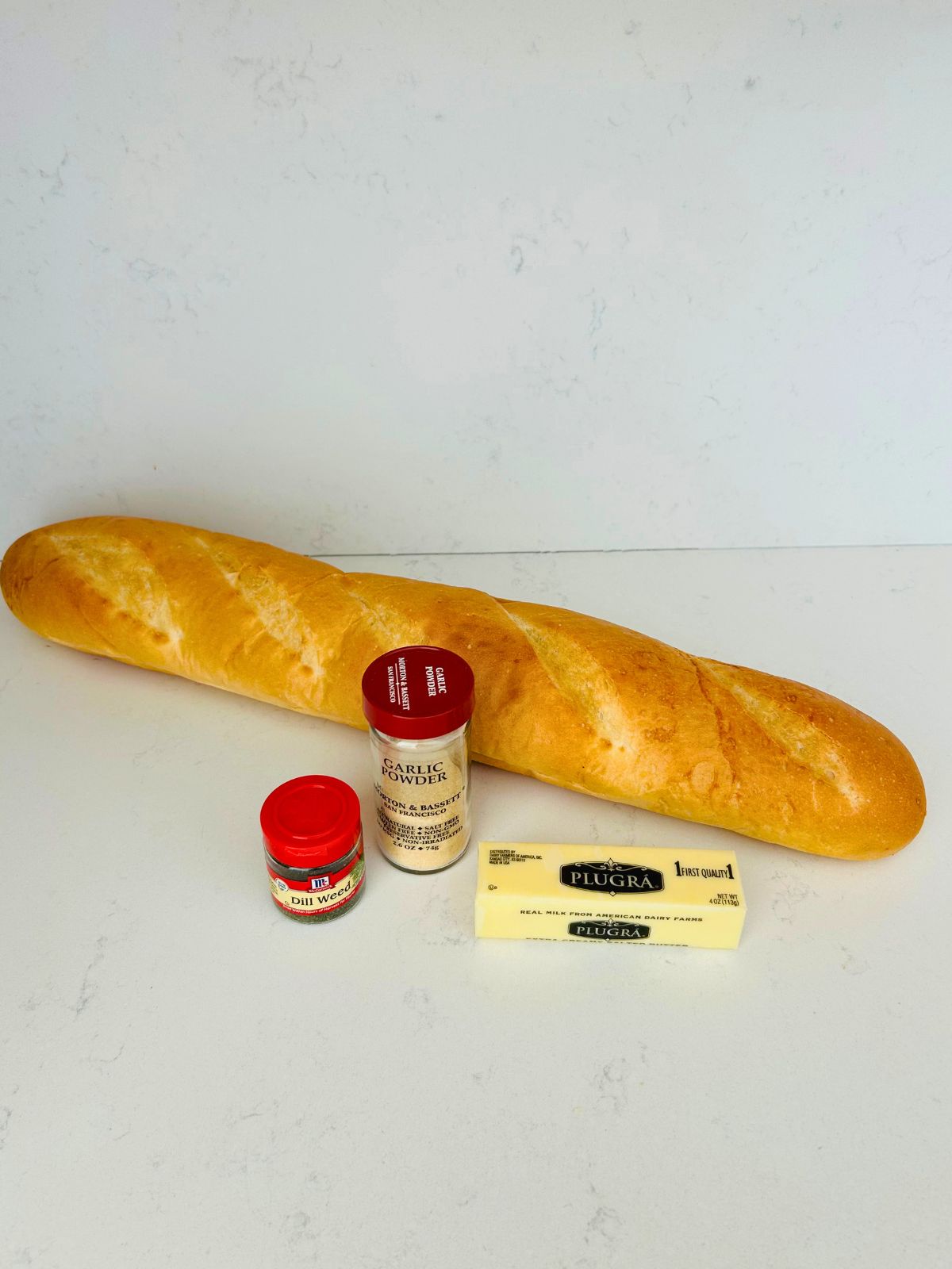 The four ingredients needed to make easy garlic bread on the countertop.