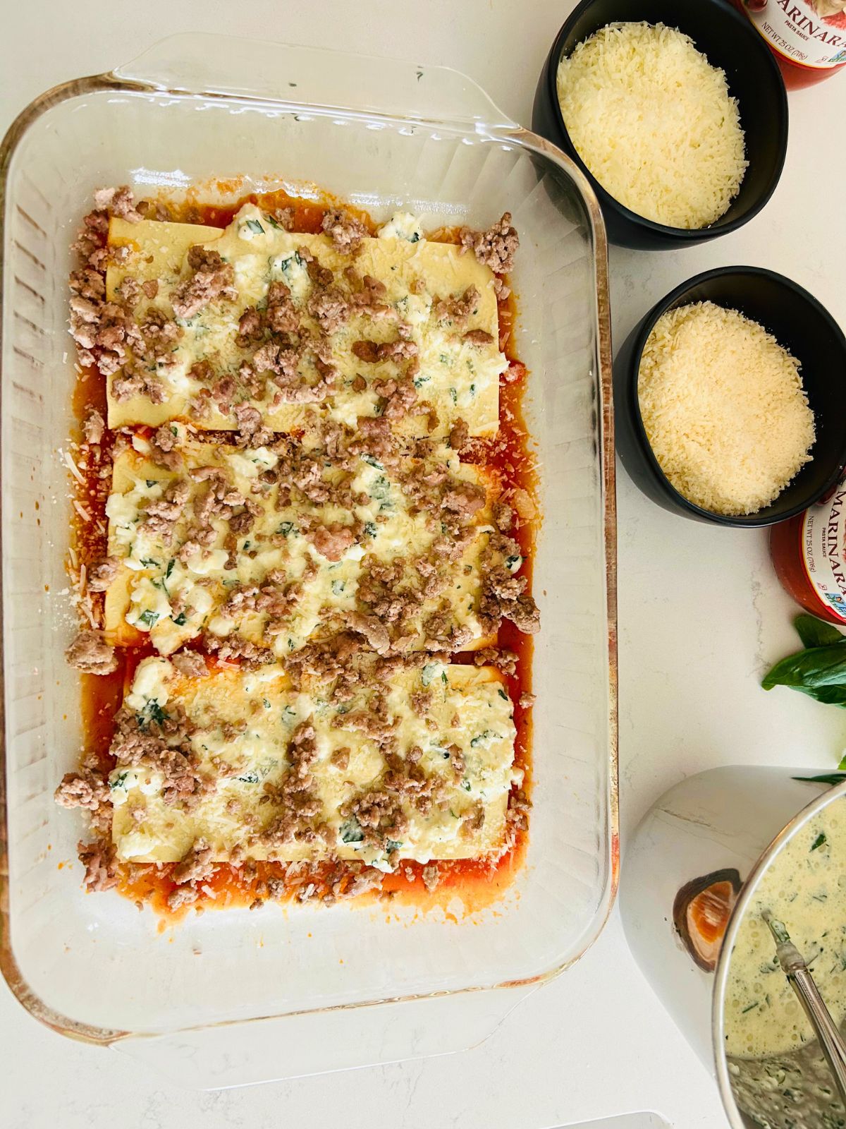 Cooked ground meat sprinkled over cottage cheese, Pecorino, and Parmigiano Reggiano cheese and no boil lasagna noodles.