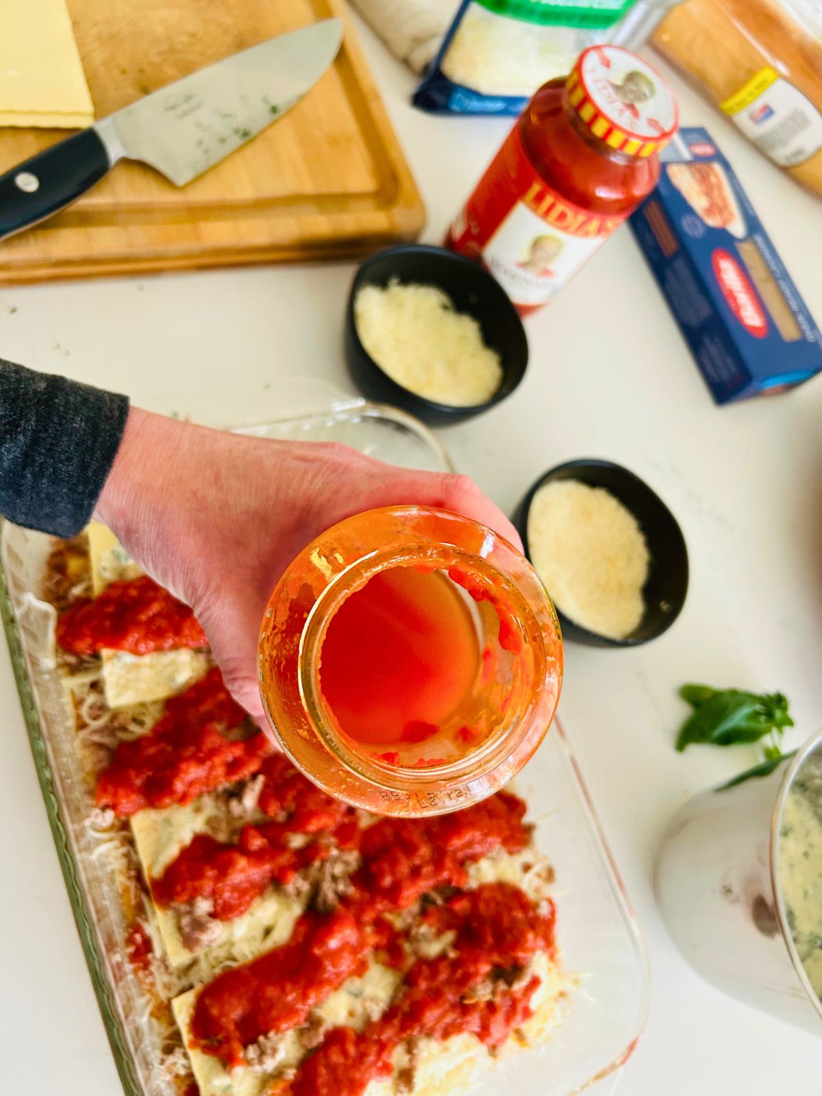 Water has been slushed inside an empty marinara jar to get the remaining sauce out and pour over the lasagna before baking it.