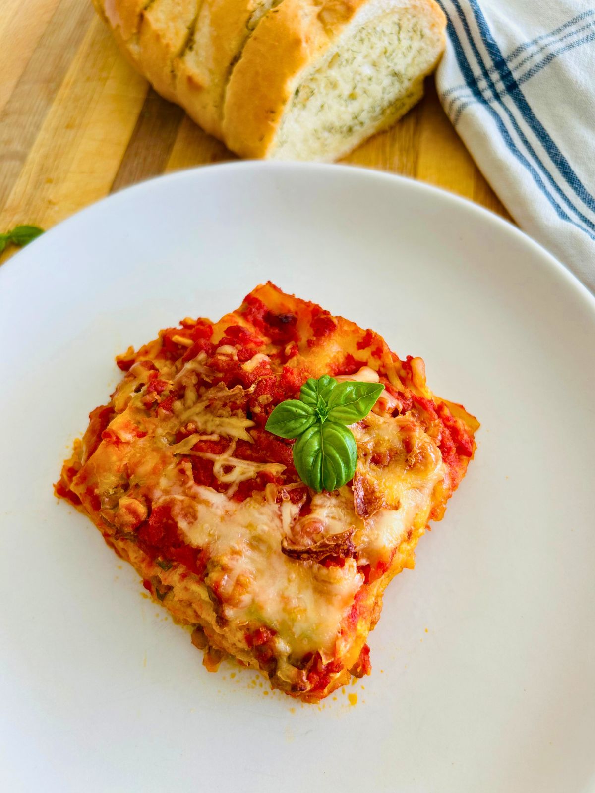 A slice of four cheese lasagna with basil on top.