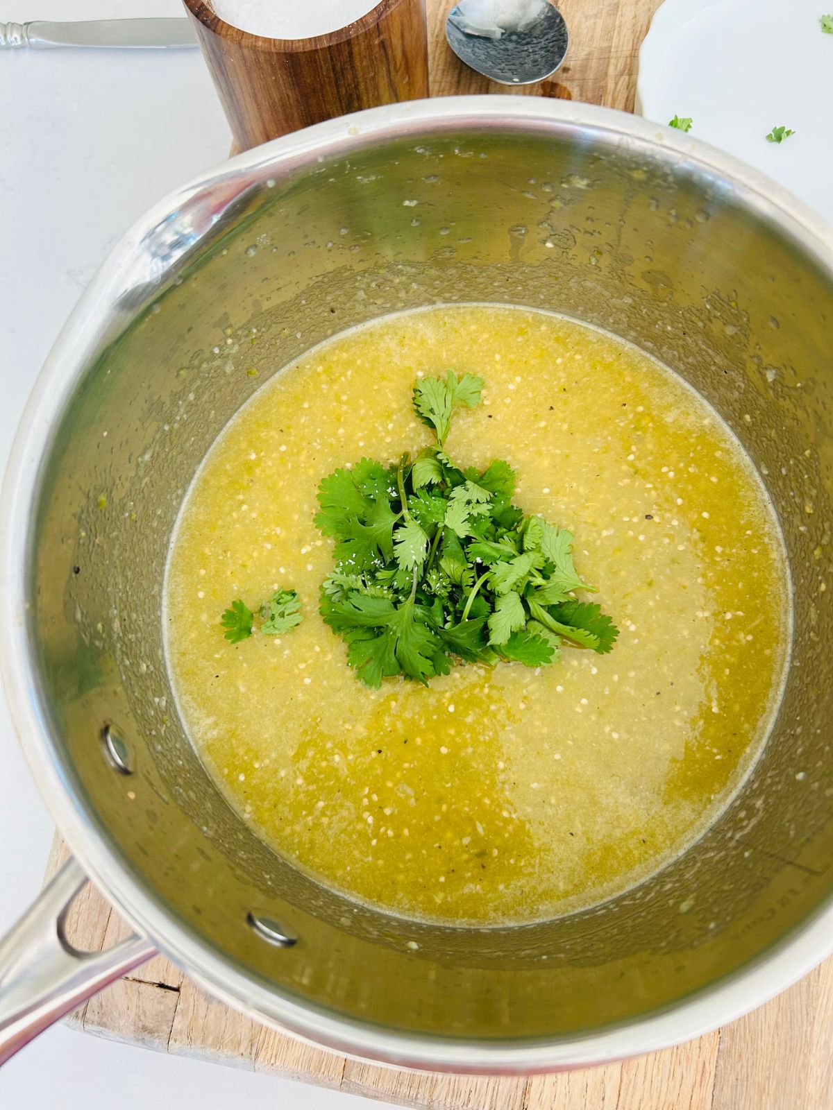 A small bunch of cilantro leaves on top of the pureed green salsa verde inside a saucepan.