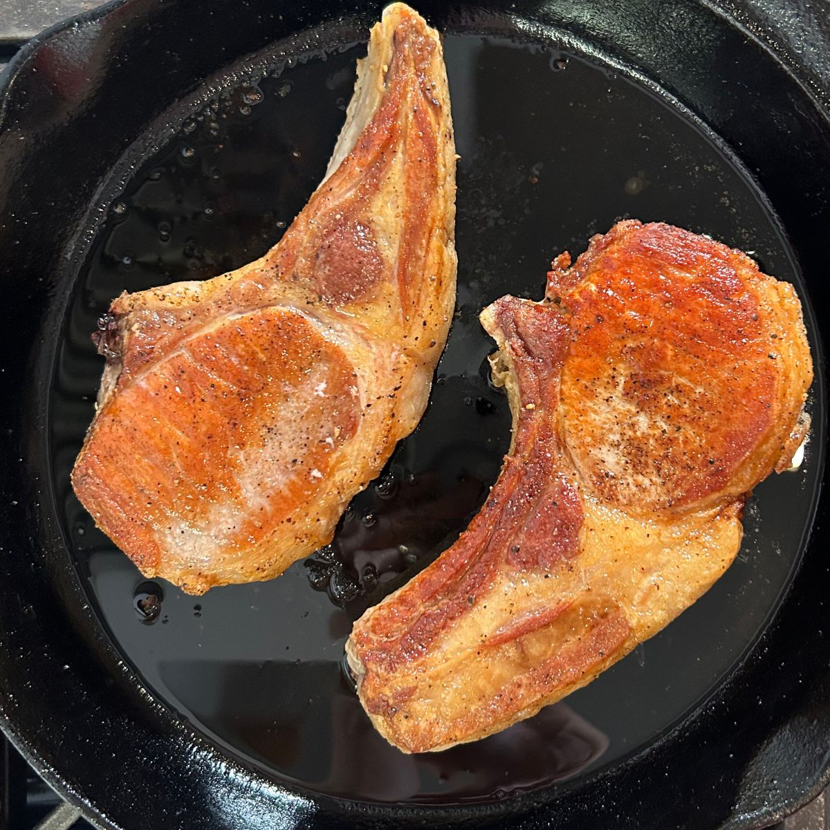 Pan seared pork chops in a cast iron skillet.