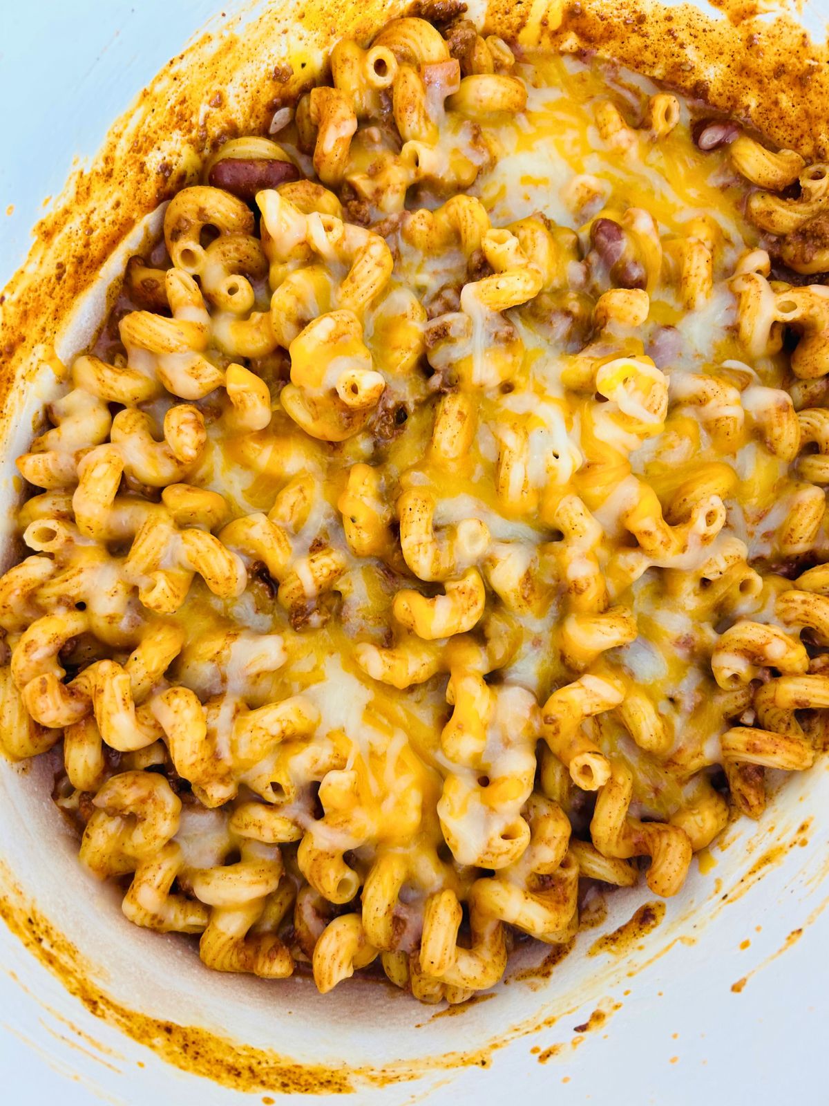 Melted shredded cheese over the chili mac in a pot.