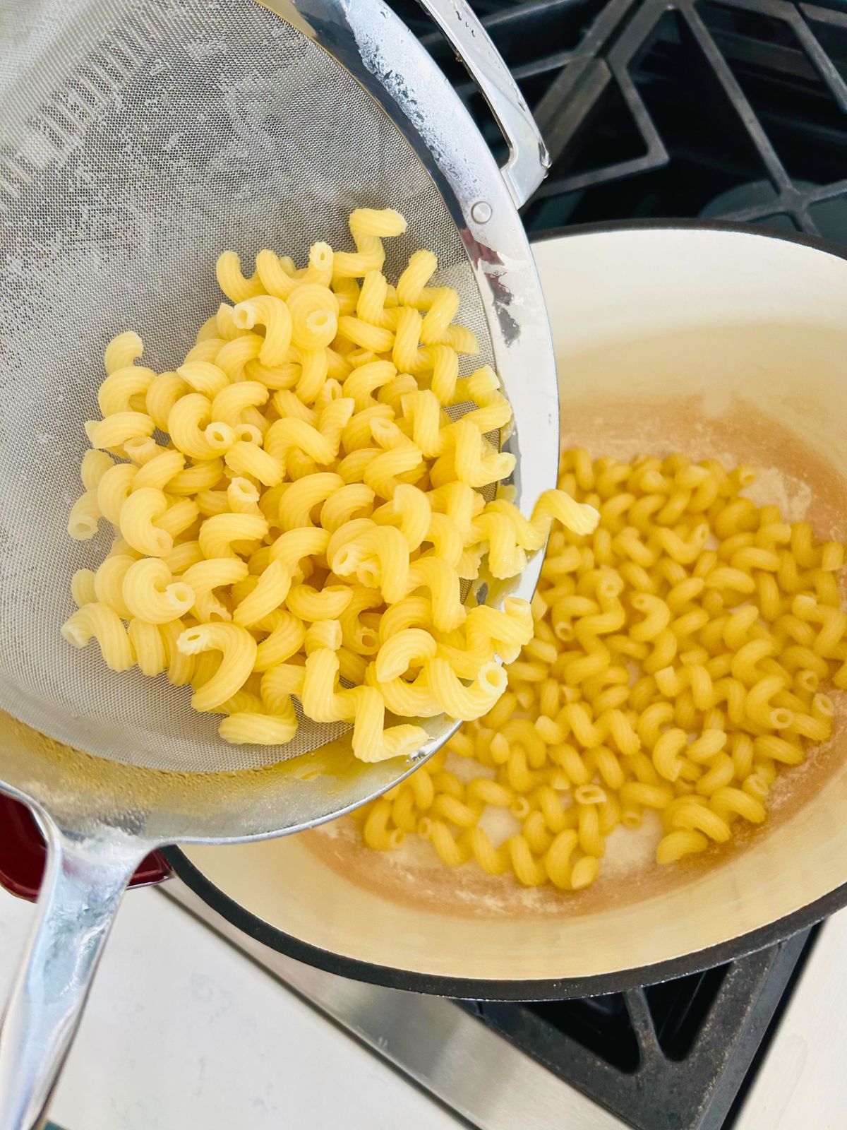 Drained, cooked, cavatappi shaped pasta in a strainer being poured back to the pot.