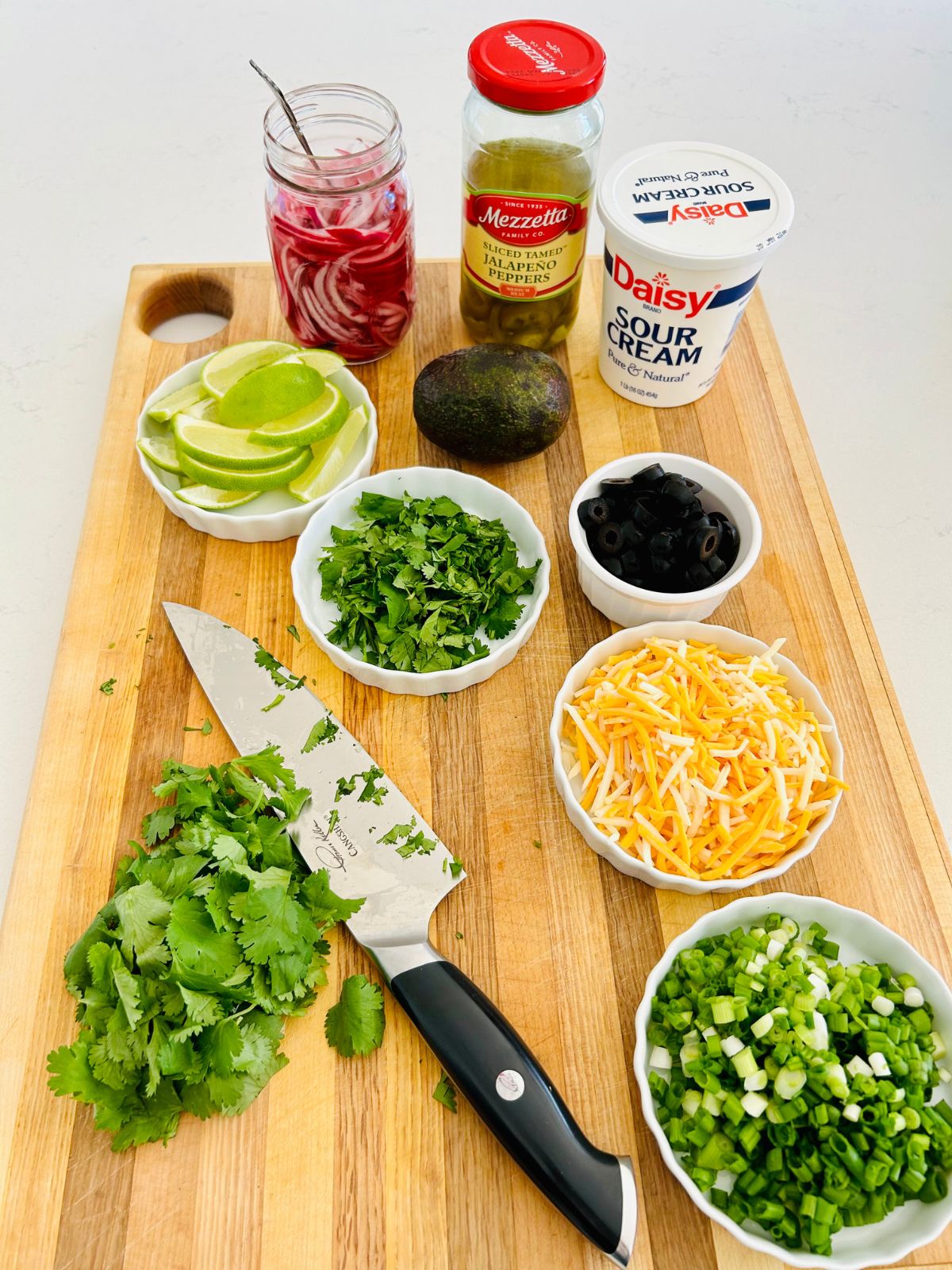 Shredded cheese, green onions, cilantro, black olives, limes, avocado, sour cream, pickled red onions, sliced jar of jalapenos for chili toppings.