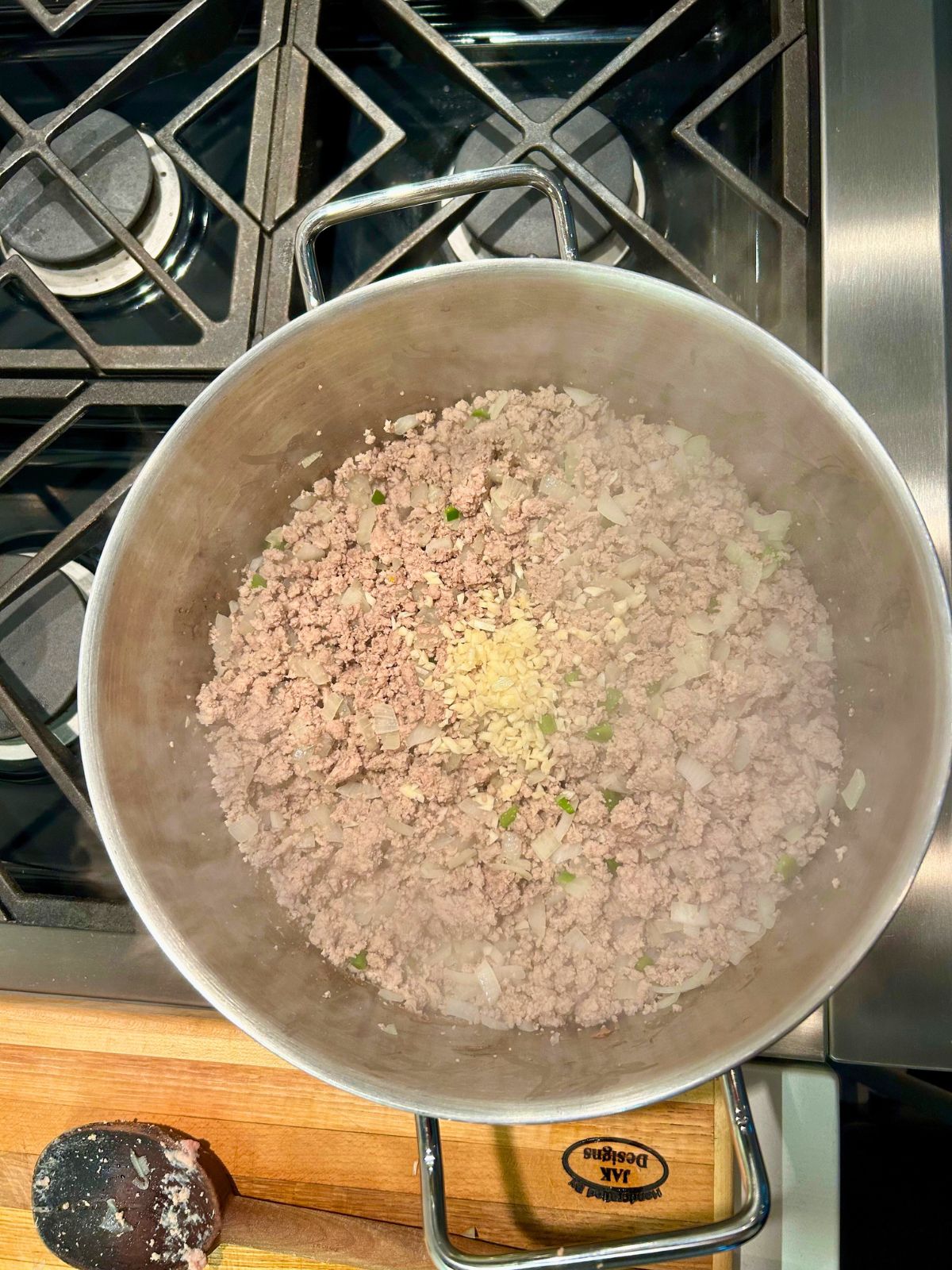 Minced onion added to a pot of cooked meat, onions, and jalapenos.