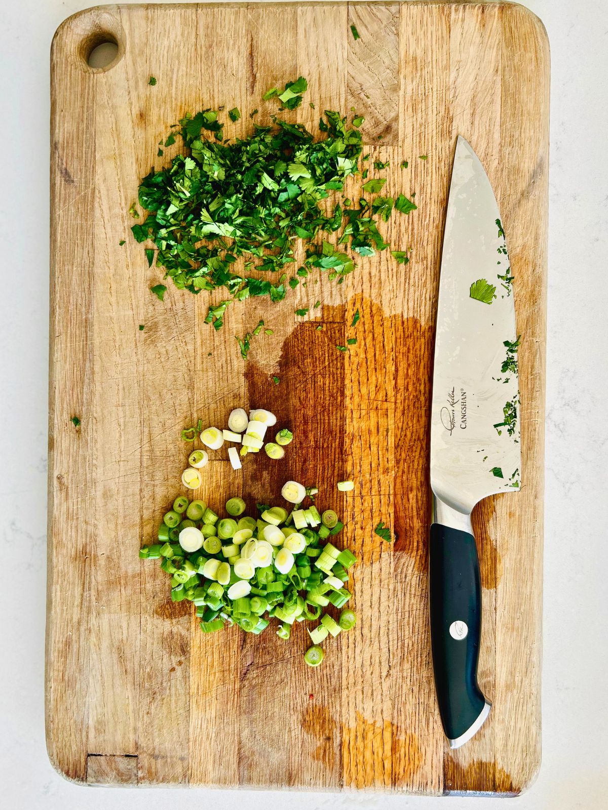 Finely chopped cilantro and thinly sliced green onions next to a knife.