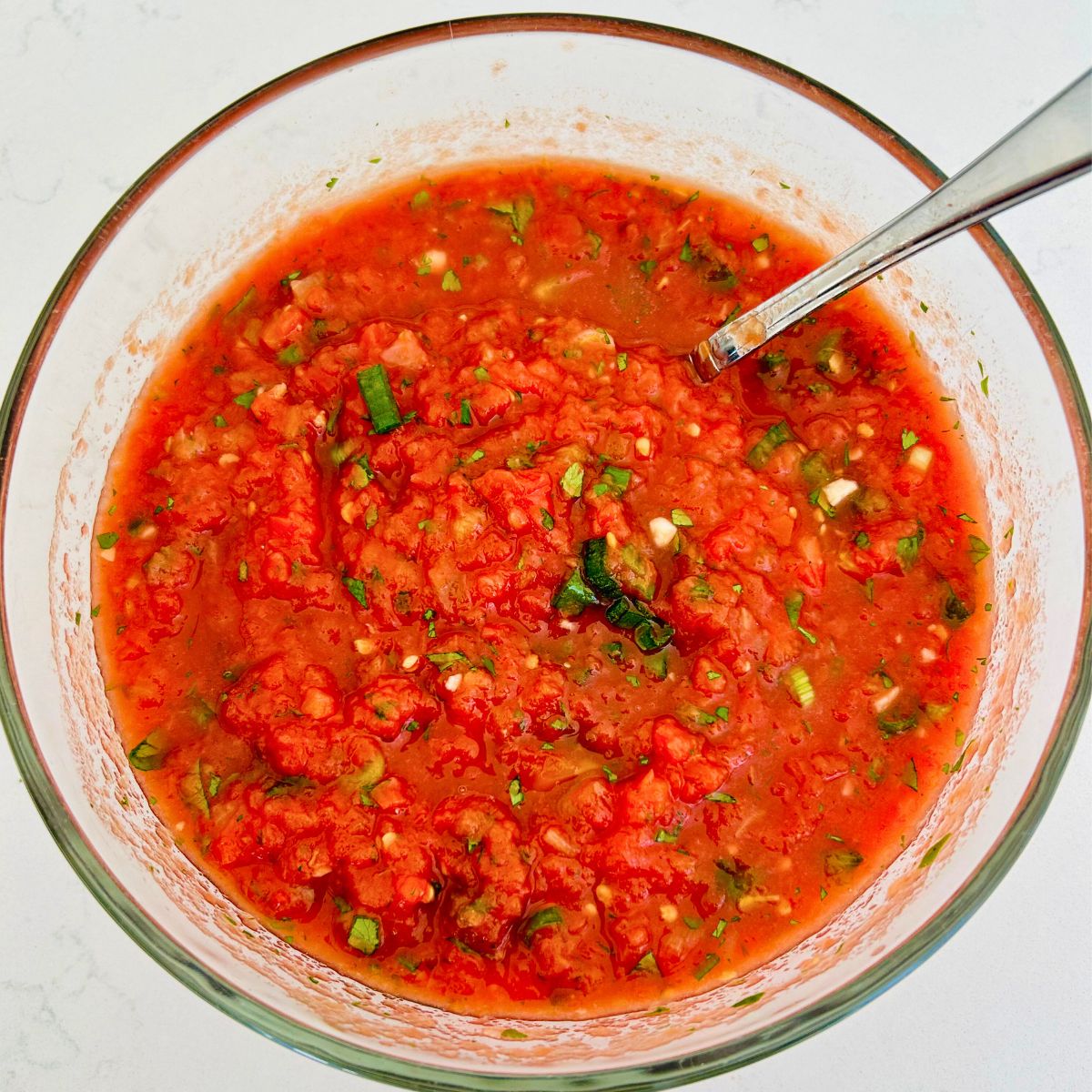 A large clear bowl with the restaurant style salsa in it.