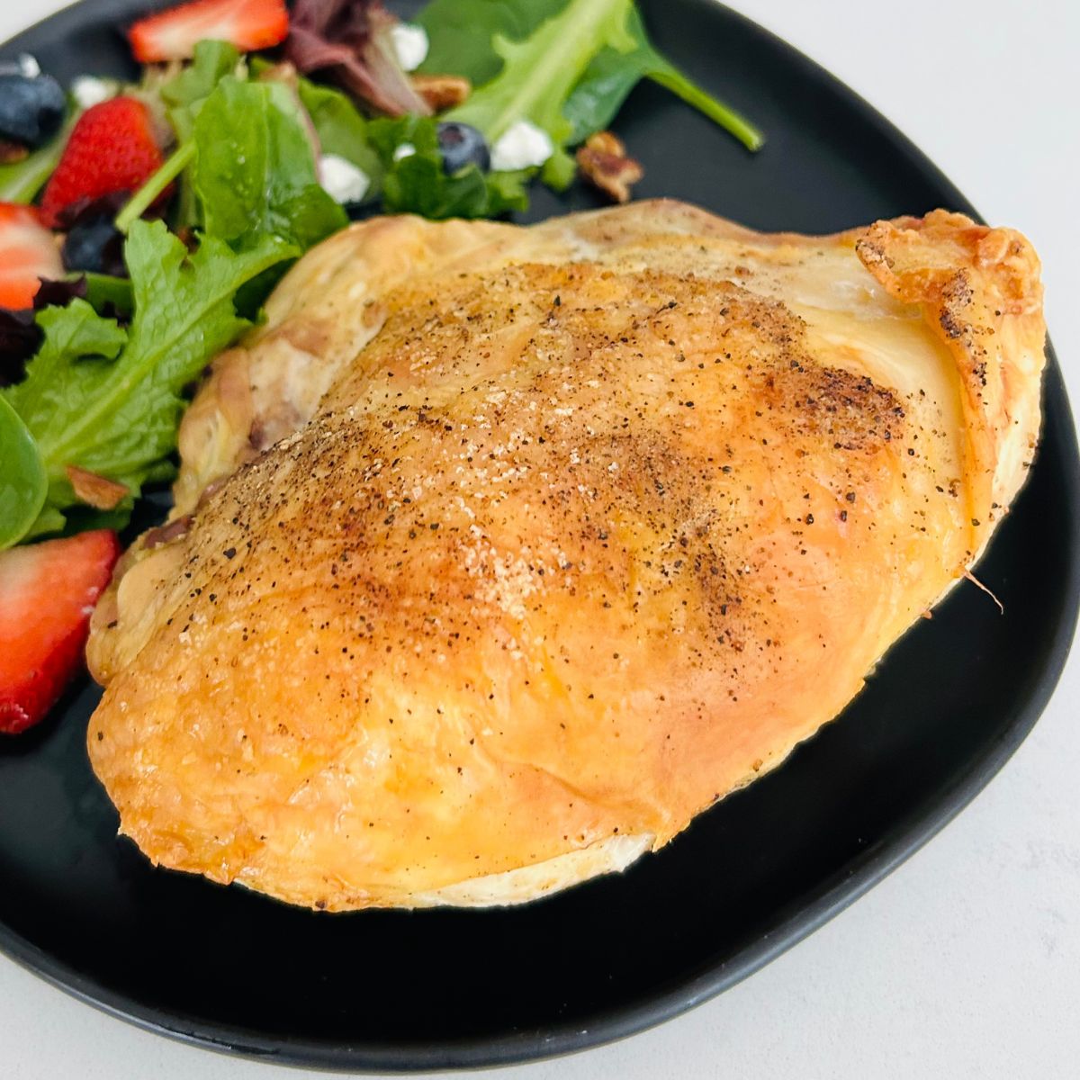 Sheet pan bone-in chicken breast next to a salad on a black plate.