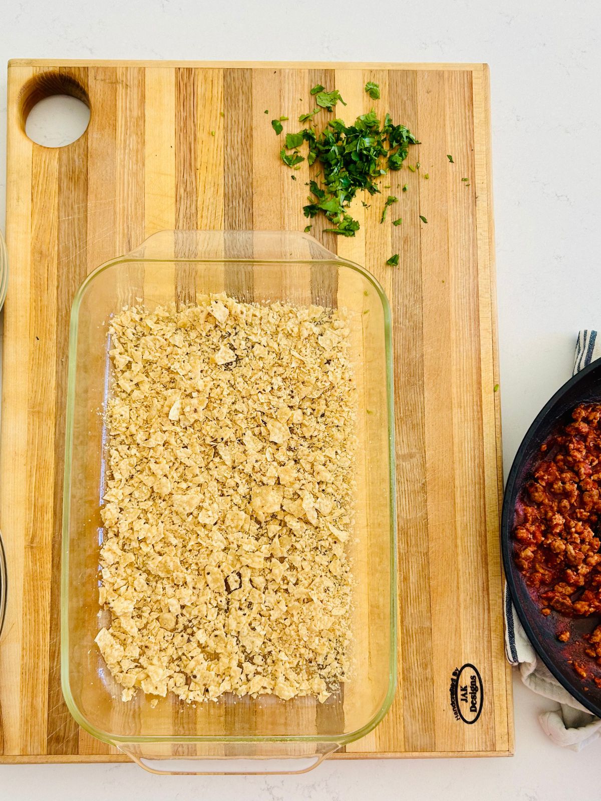 Crushed tortilla chips are the first layer in the Pyrex casserole dish.