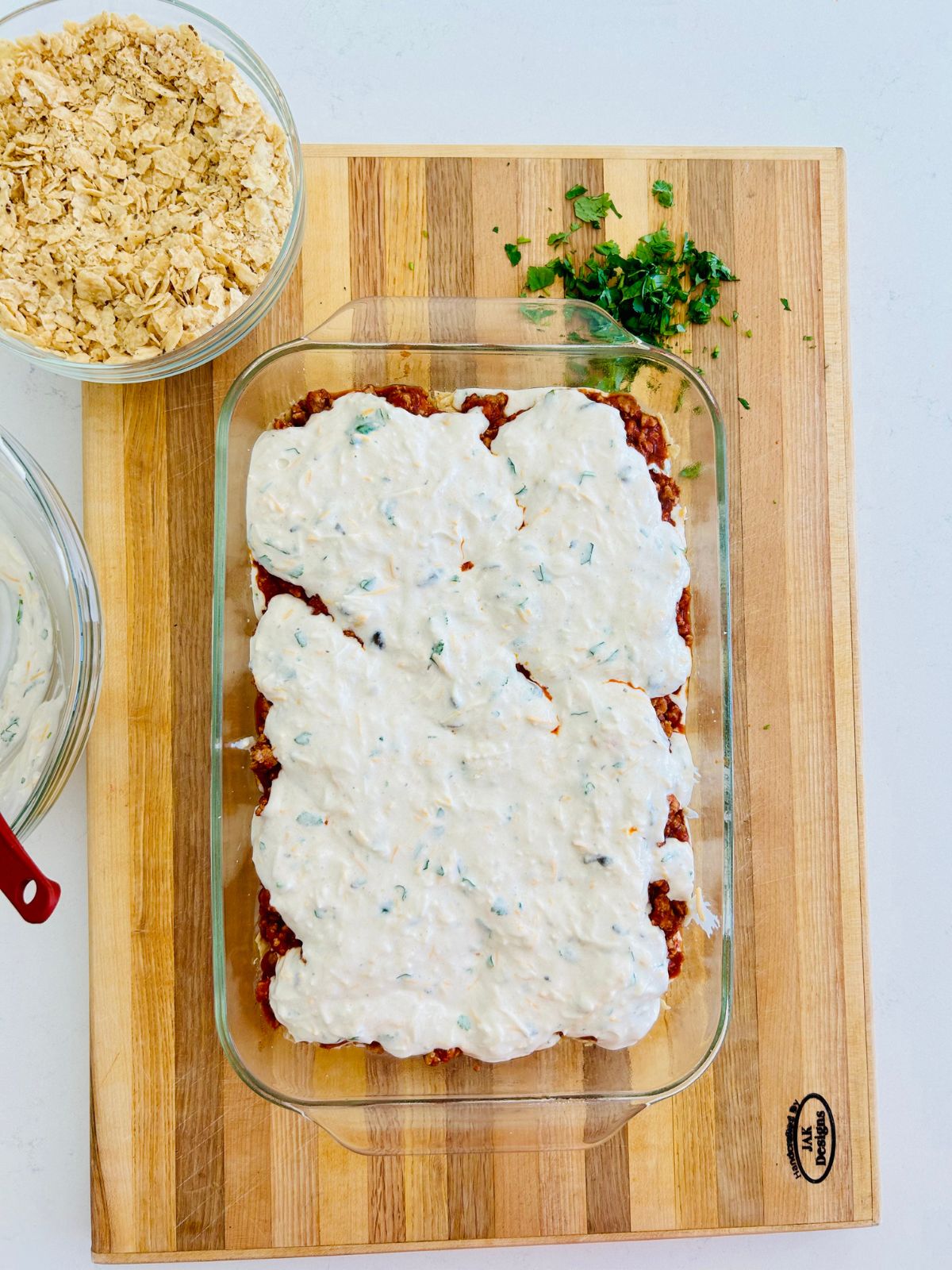 The fourth layer of the taco casserole has been added to the baking dish, which is the sour cream and cheese sauce.