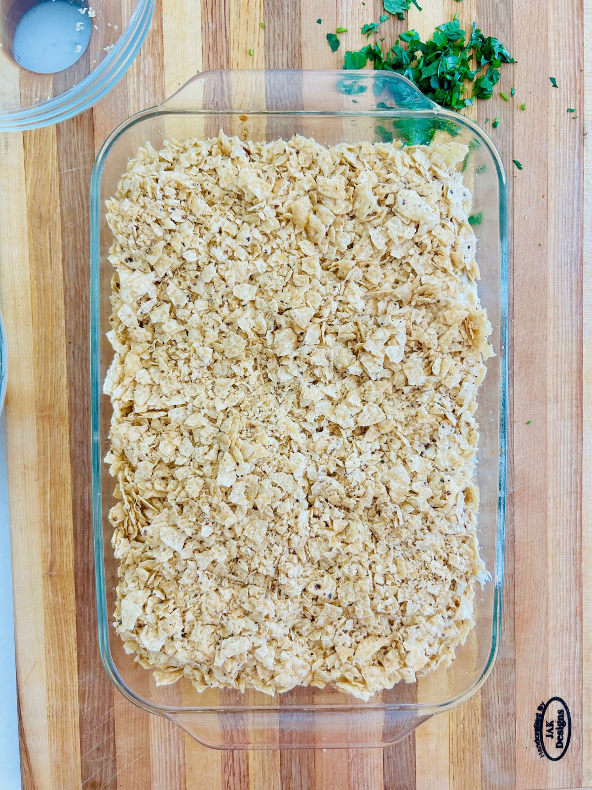 The taco casserole is fully assembled and ready to bake in the oven.