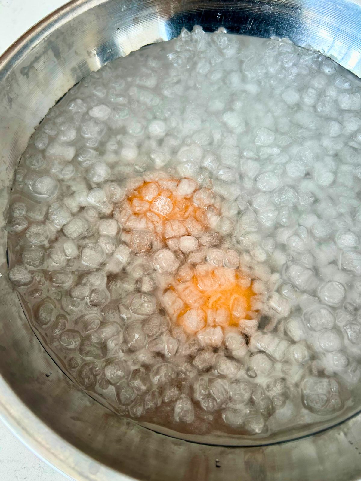 An icy water bath that contains boiled eggs that are cooling down.