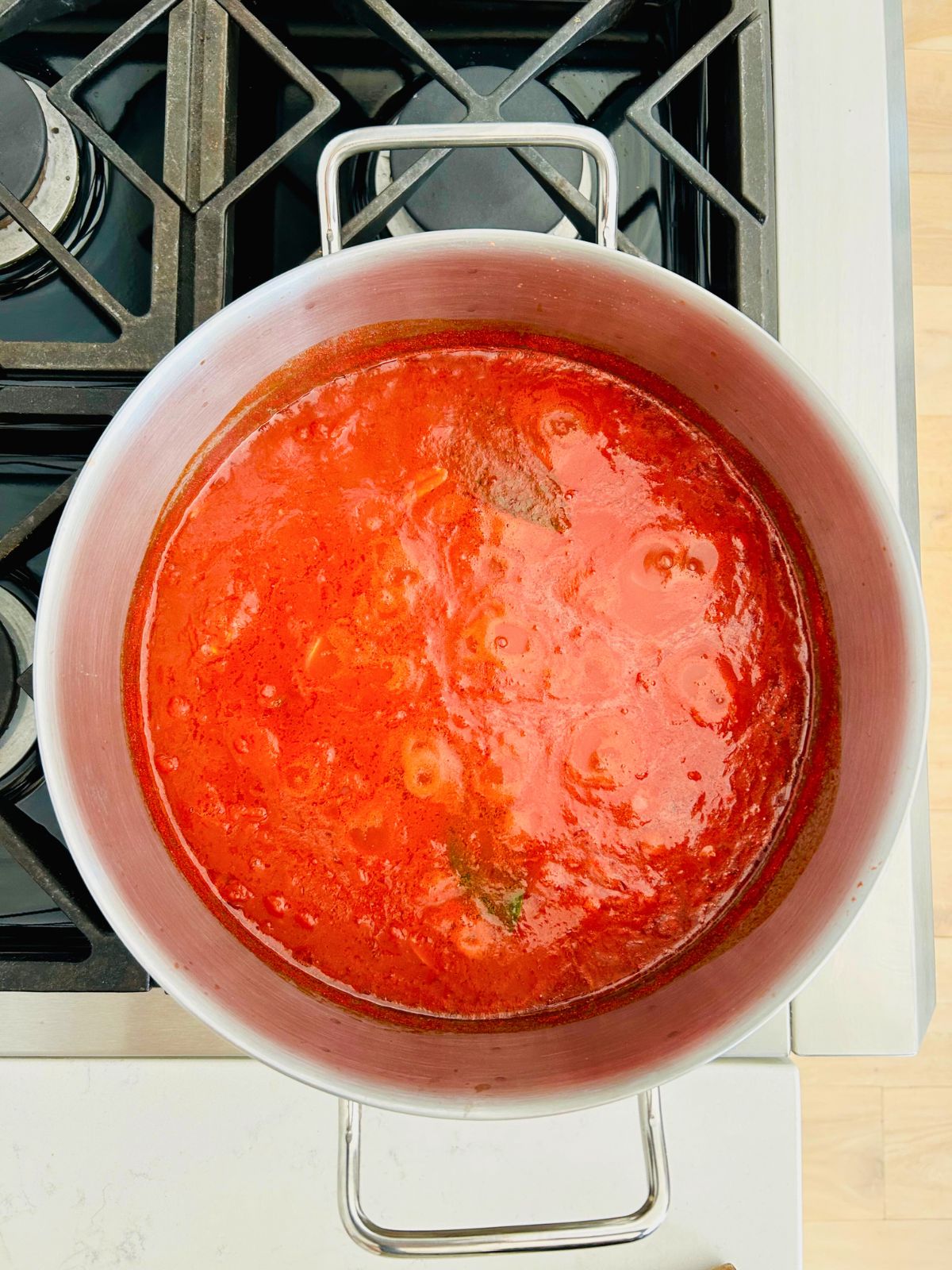 A large pot of marinara sauce simmering on the stove.