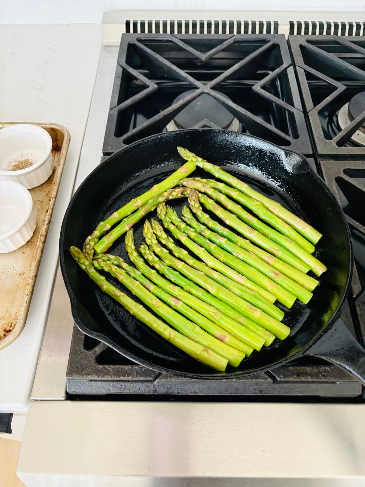 The asparagus is an even layer in the hot cast iron skillet.