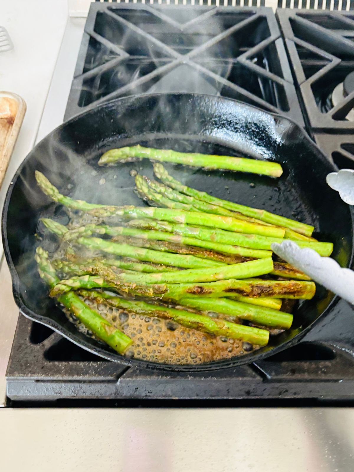 Stirring the lemon juice with the sauteed asparagus in the skillet.