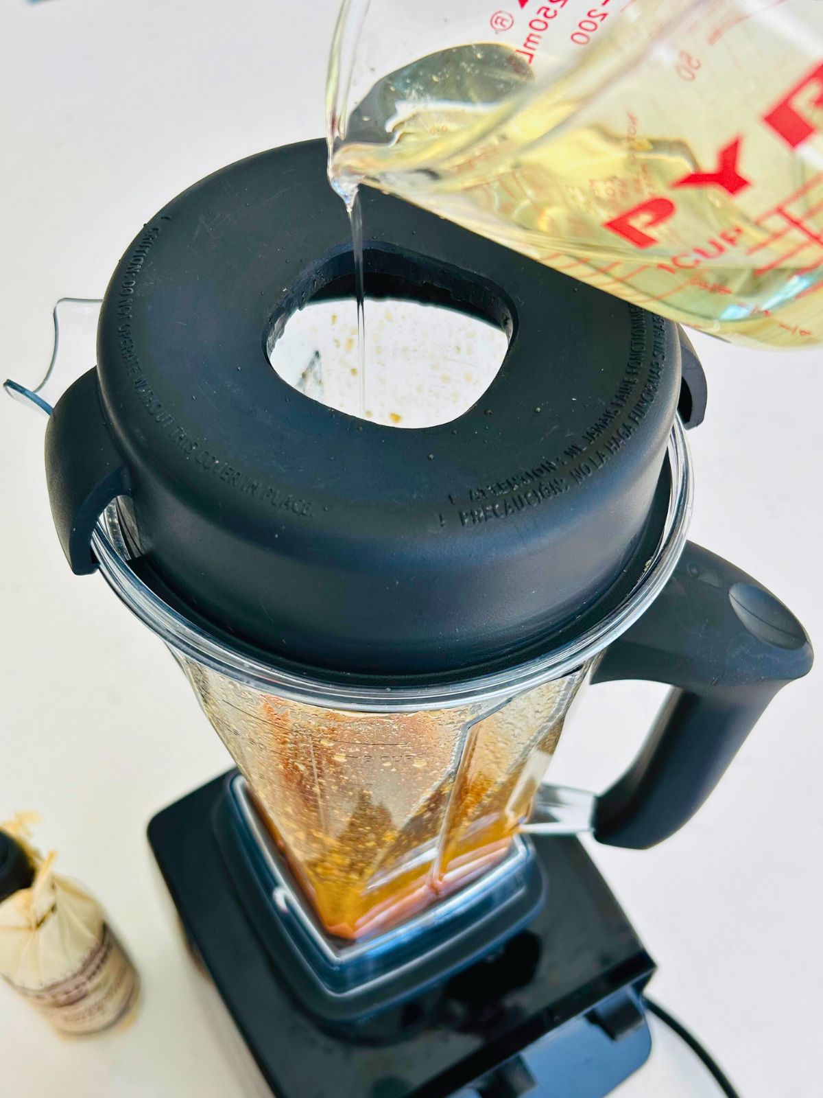 A small steam of oil is added to the vinaigrette with the motor running on the blender.