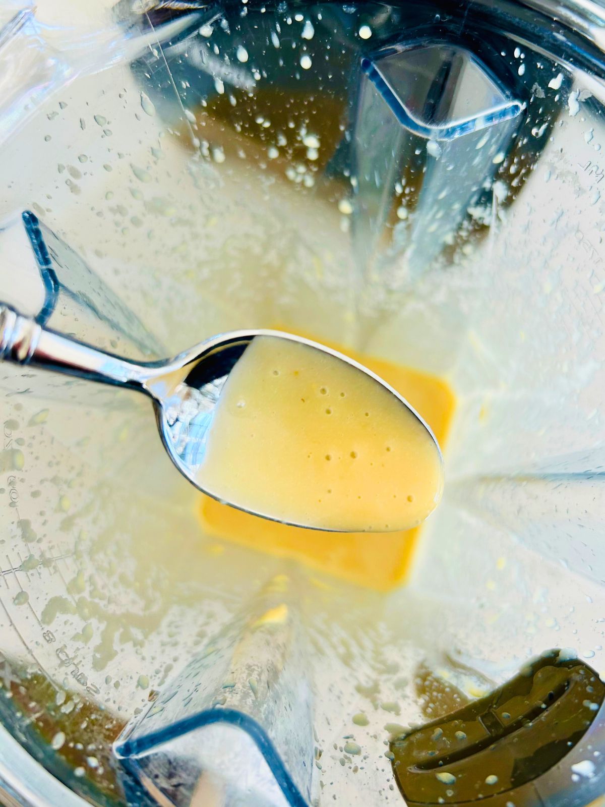 A spoonful of honey mustard dressing over the blender's pitcher.