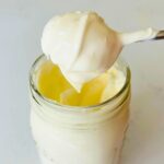 A thick spoonful of homemade creme fraiche recipe over a mason jar.