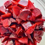 Wedges of roasted beets in foil in a clear bowl.