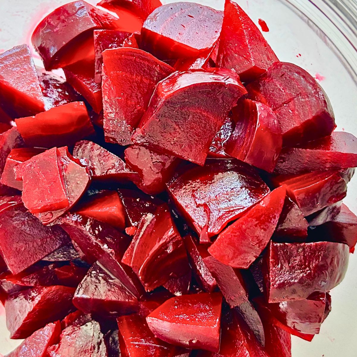 Wedges of roasted beets in foil in a clear bowl.
