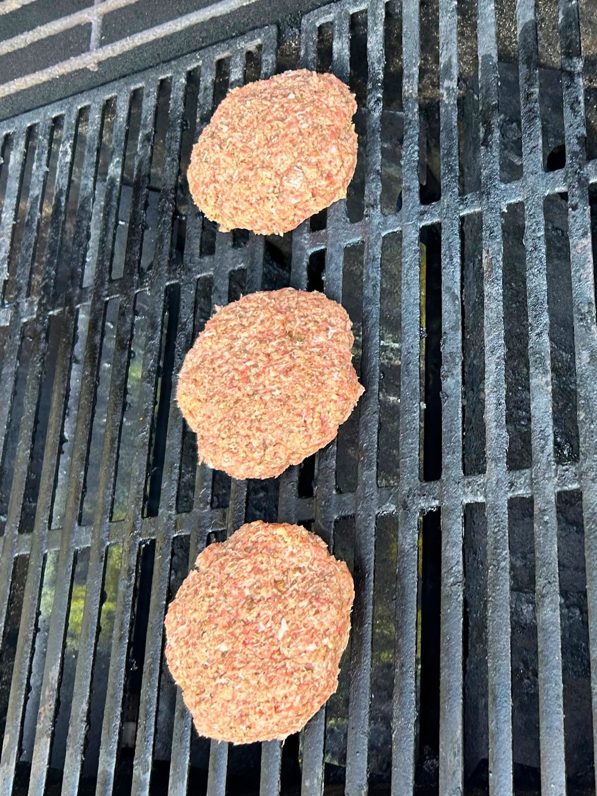 Three turkey burgers starting to cook on the gas grill.