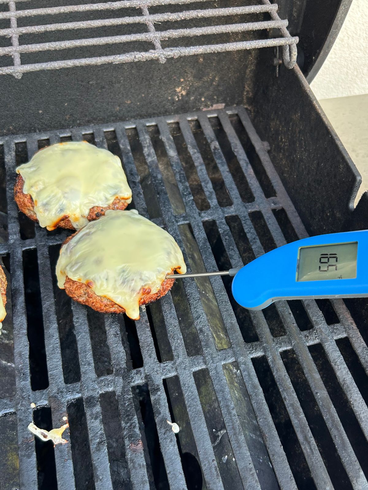 Checking the internal temperature of a turkey burger as its cooking on the gas grill.