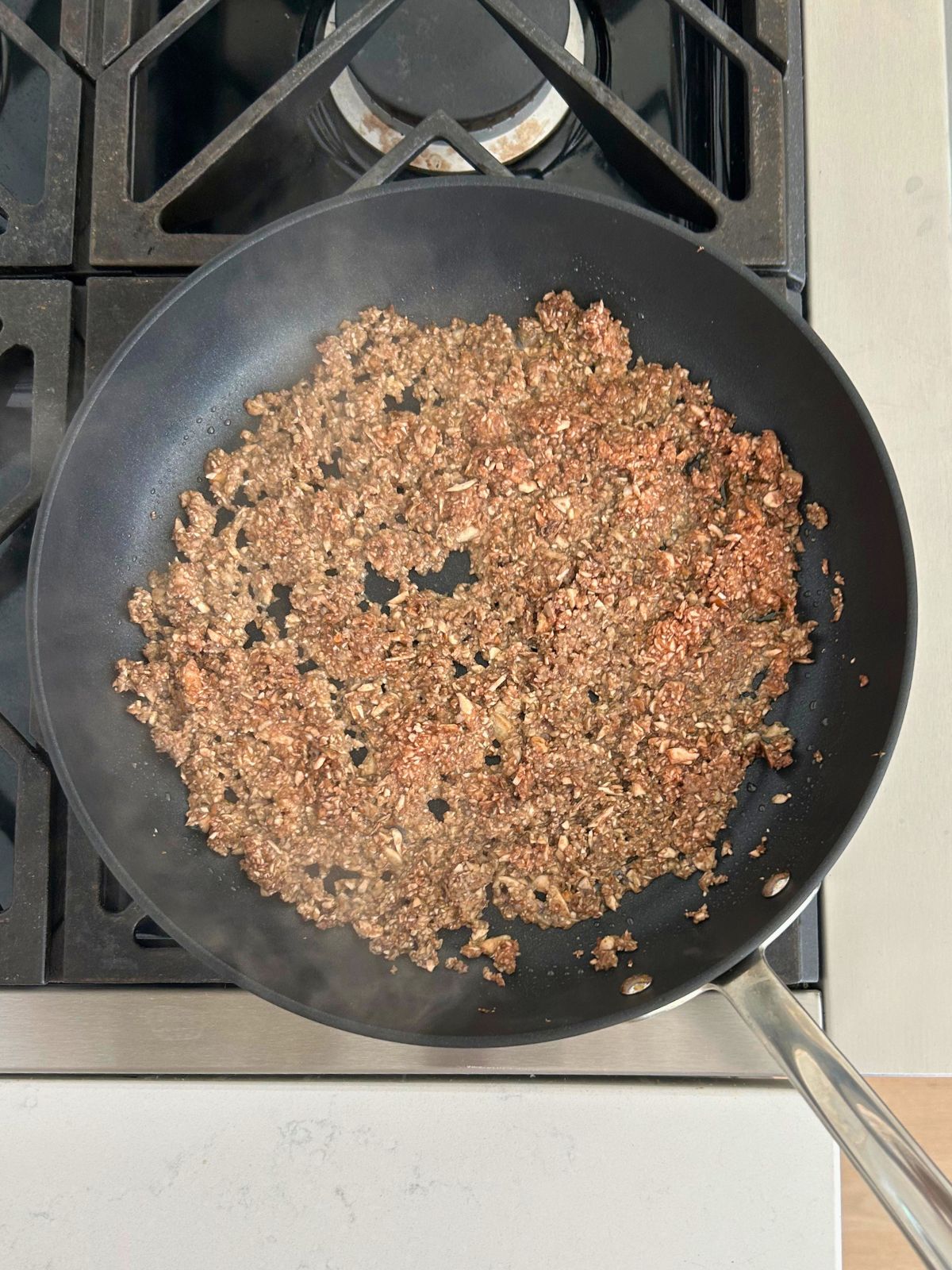 Finely chopped mushrooms are sauteing in a skillet.