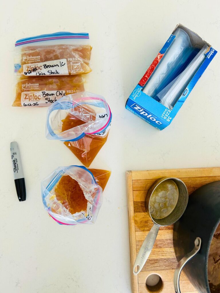 A measuring cup is used to portion small amounts of brown chicken stock to zip lock bags to freeze and use later.