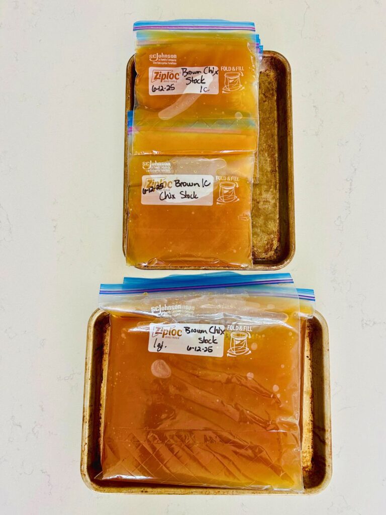 Labeled portions of brown chicken stock in freezer zip lock bags and ready to freeze.