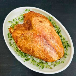 Oven roasted turkey breast with dry brine on a white oval platter with fresh thyme sprigs.