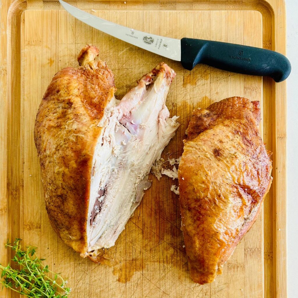 One of the breasts has been removed and laying next to the remaining oven roasted turkey breast carcass.