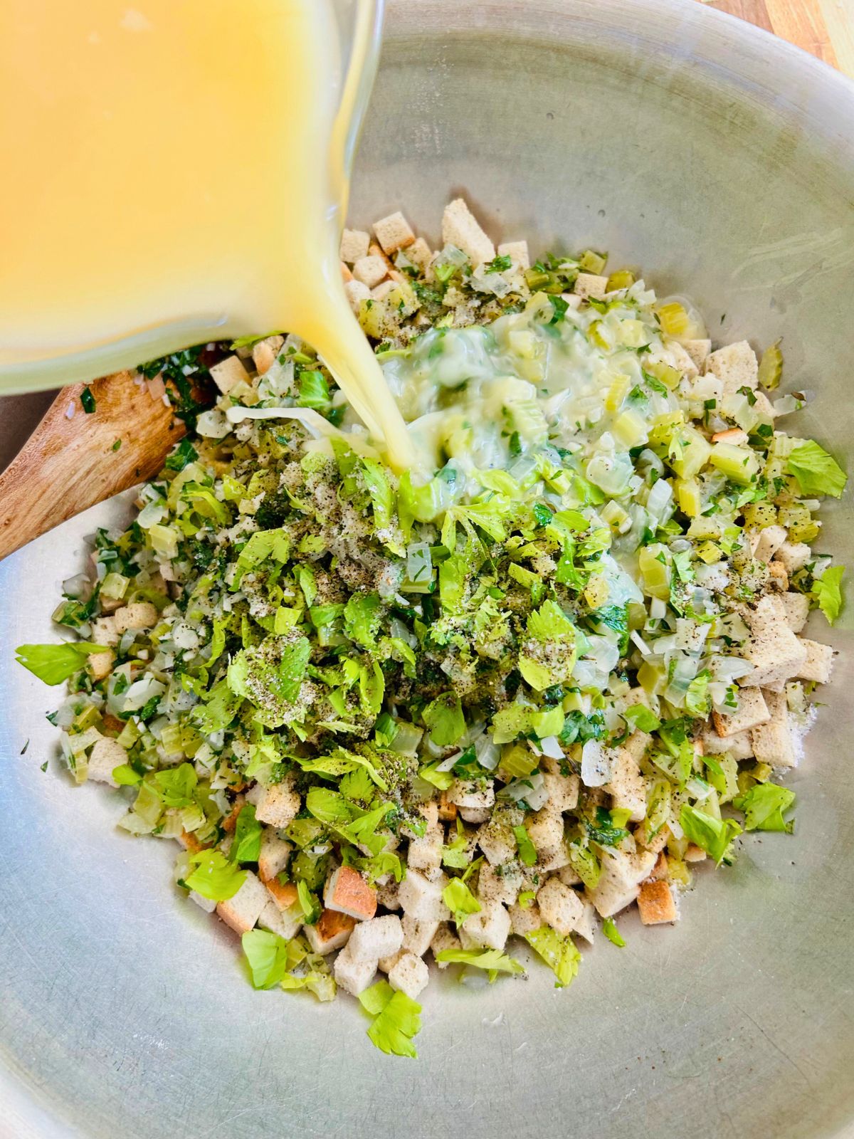 A mixture of eggs and chicken broth are poured over the cubed bread, vegetables, and herbs.