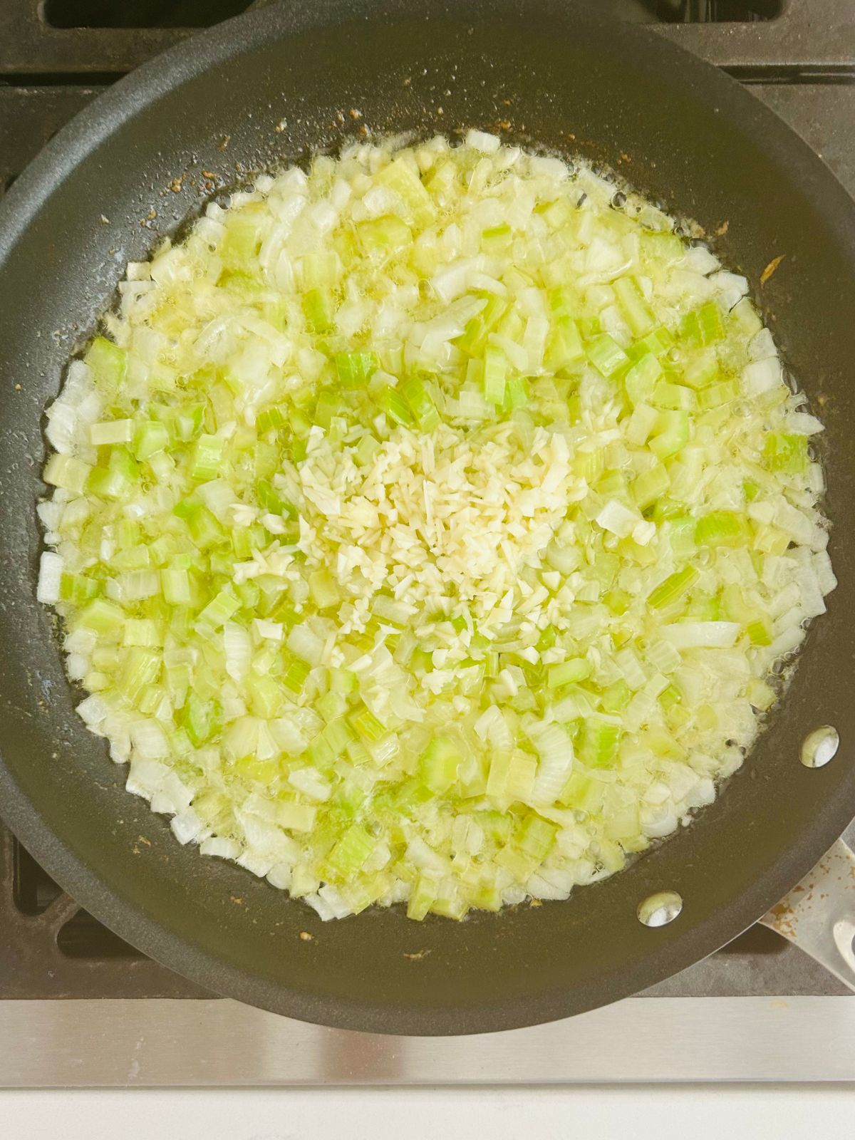 Minced garlic is added to chopped onions and celery cooked in a skillet with butter for stuffing.