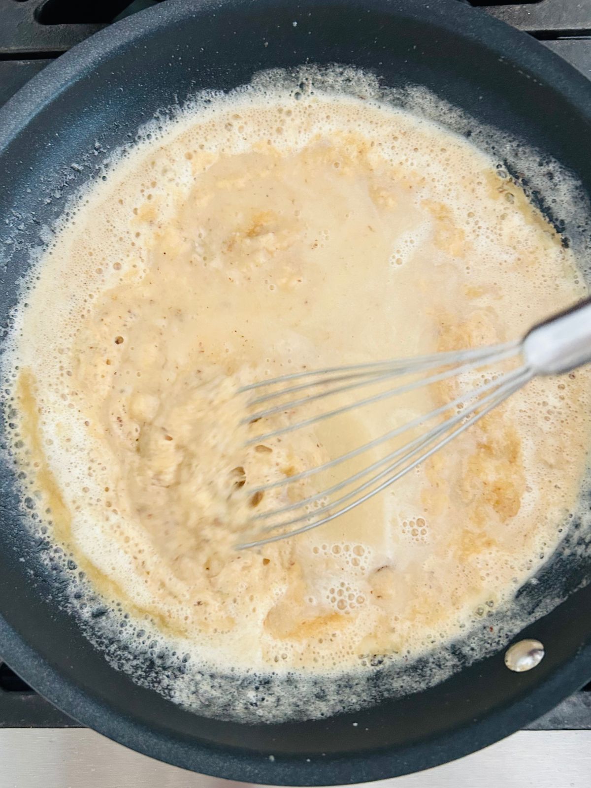 Wine is being whisked into a skillet of roux.