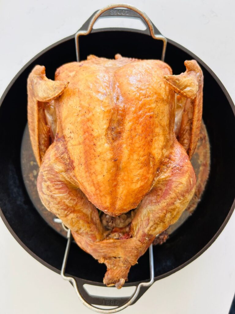 Roasted turkey resting on a rack in a cast iron skillet.