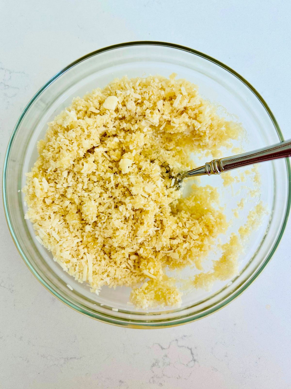 Panko bread crumbs, parmesan cheese, and butter combined in a glass mixing bowl.
