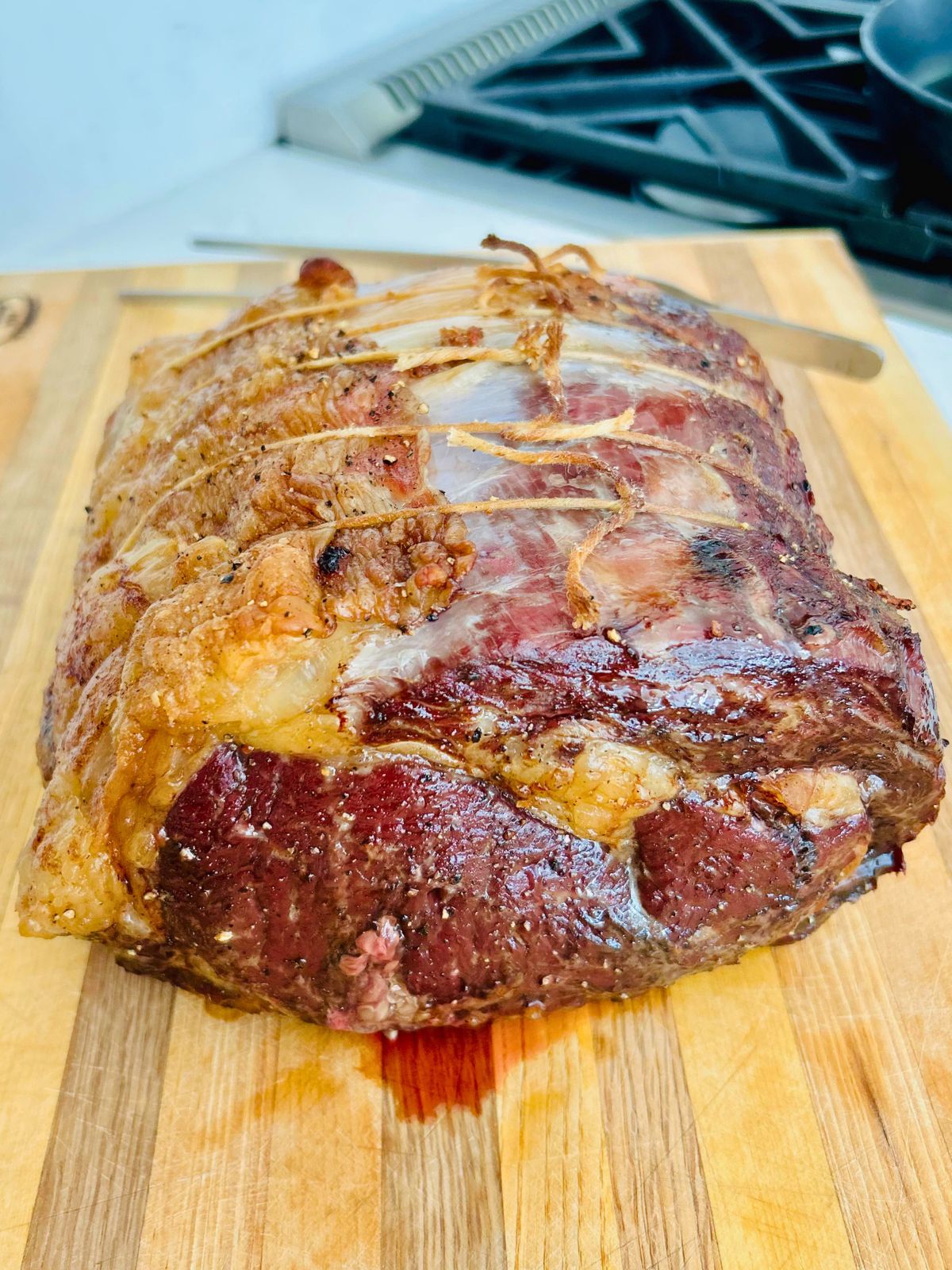 Prime rib that has been slow roasted and reverse seared resting on a cutting board.