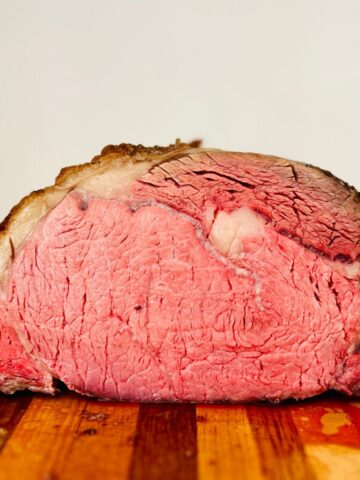 The cut side of a slow roasted prime rib recipe resting on a cutting board.