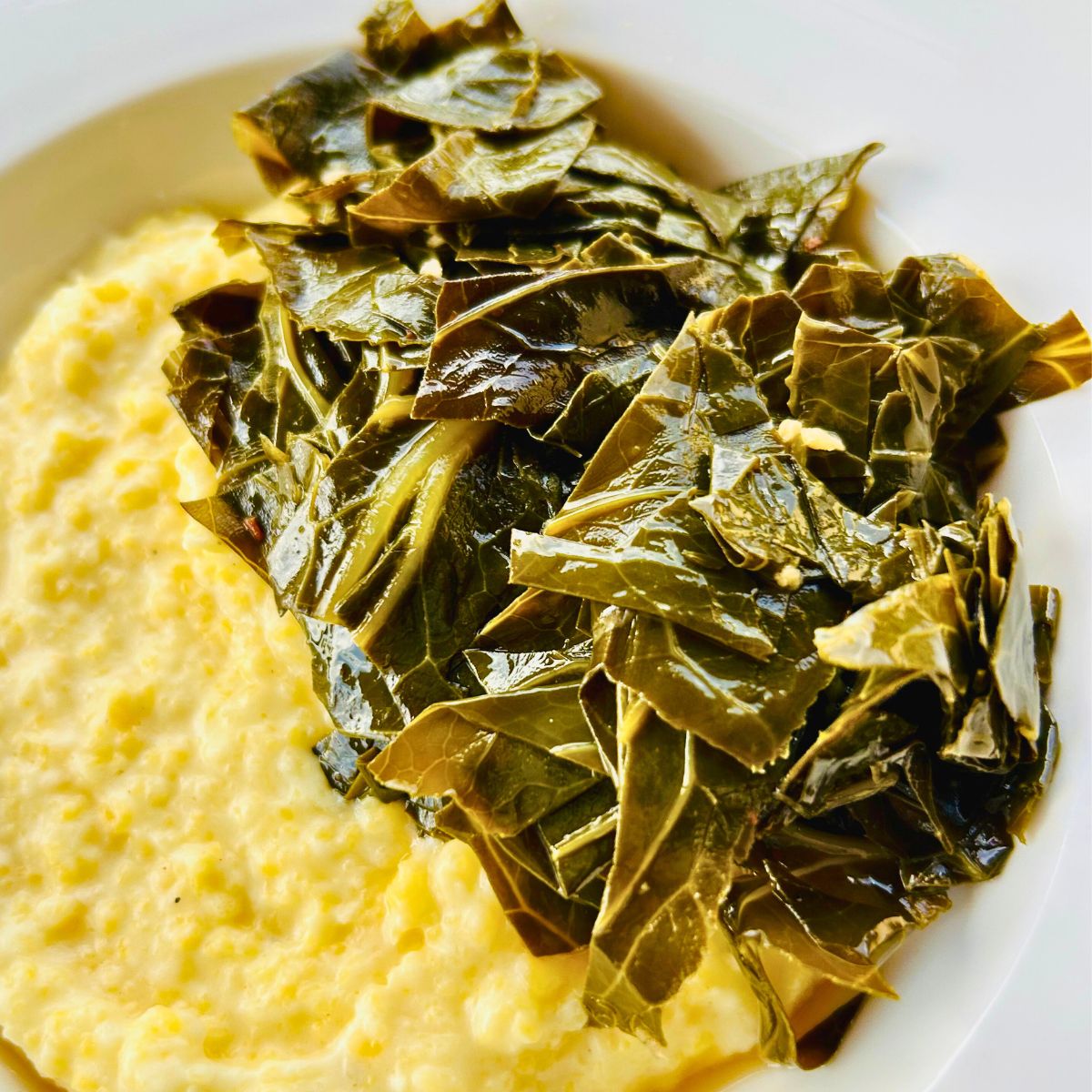Braised collard greens without pork and polenta in a white bowl.