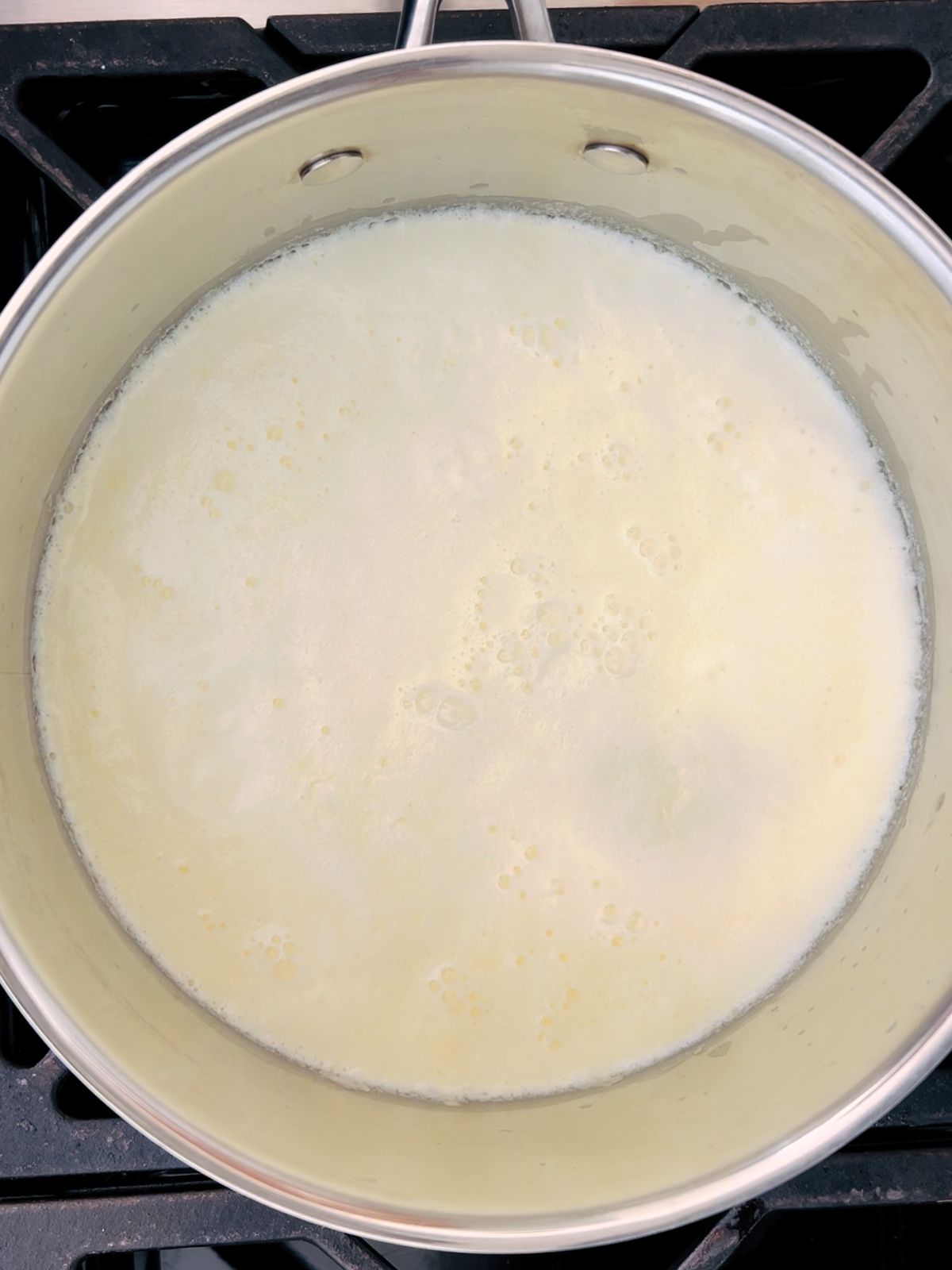 A simmering pot of cream for a chicken spiedini recipe.
