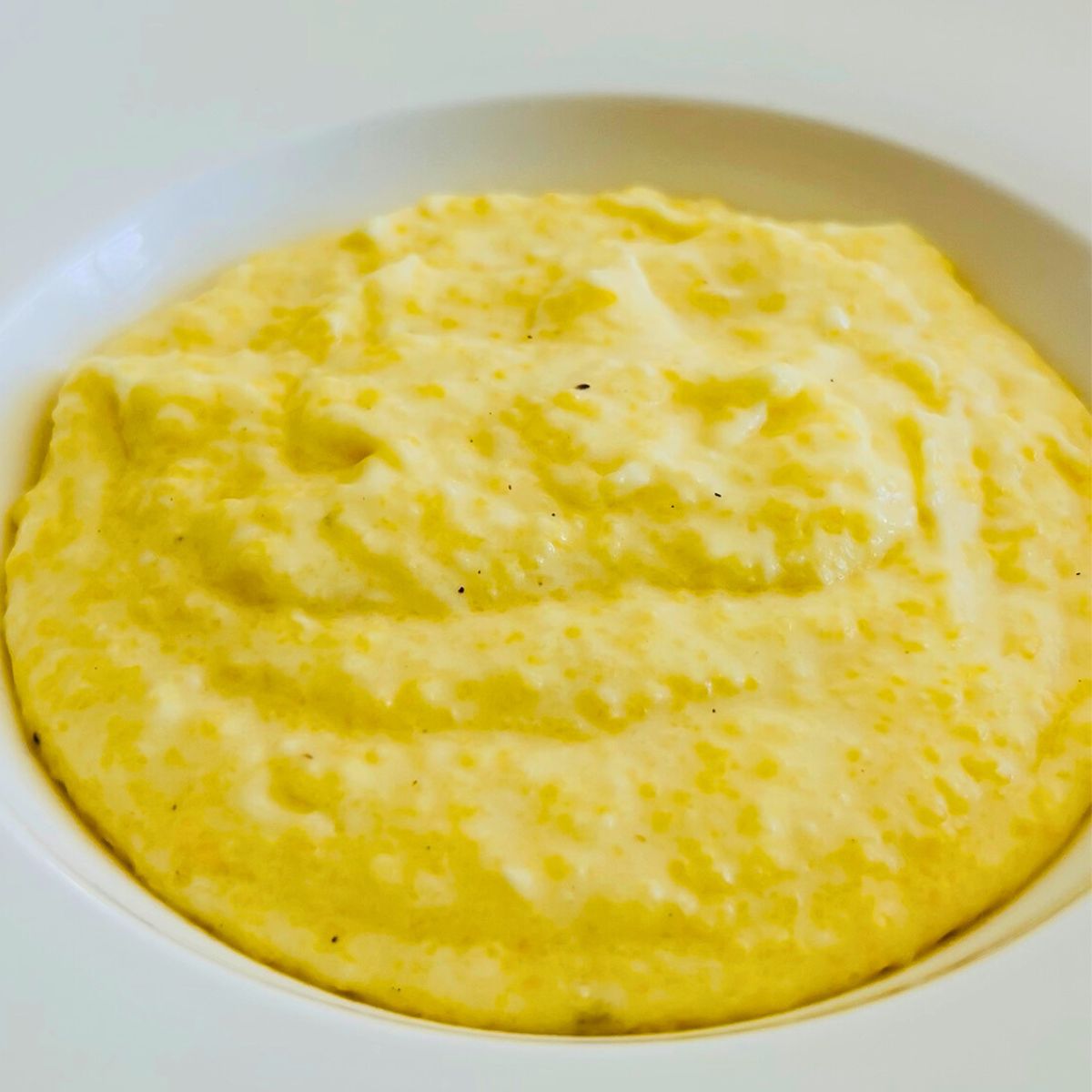 Creamy polenta with mascarpone cheese in a white bowl.