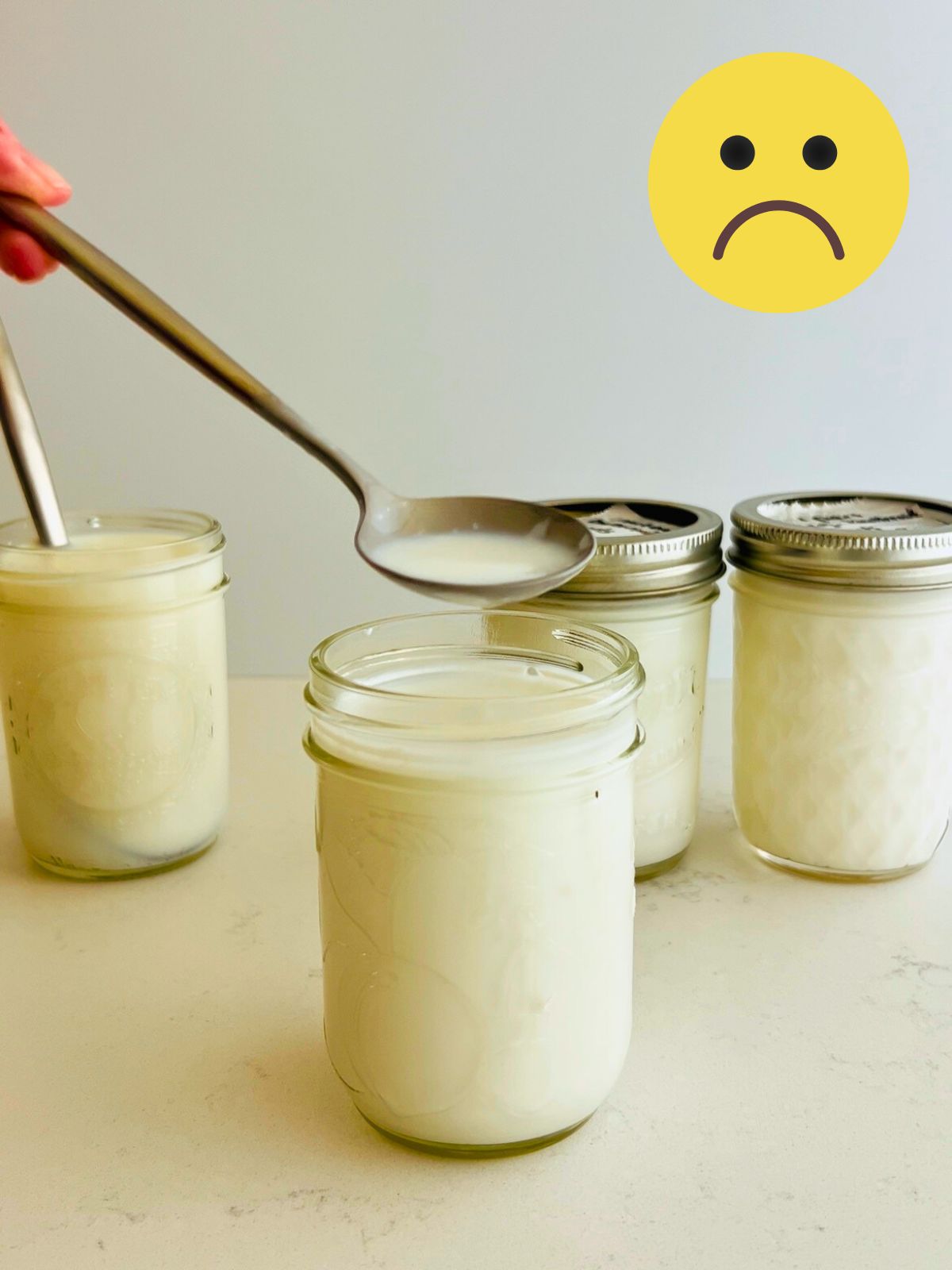 A spoon of a failed batch of cultured buttermilk held over a mason jar of the contents.