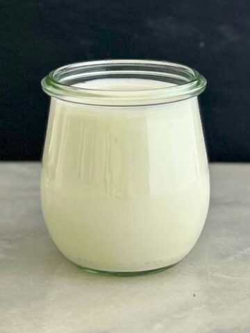 A recipe about how to make cultured buttermilk, with the finished buttermilk stored in a tulip-shaped glass jar.