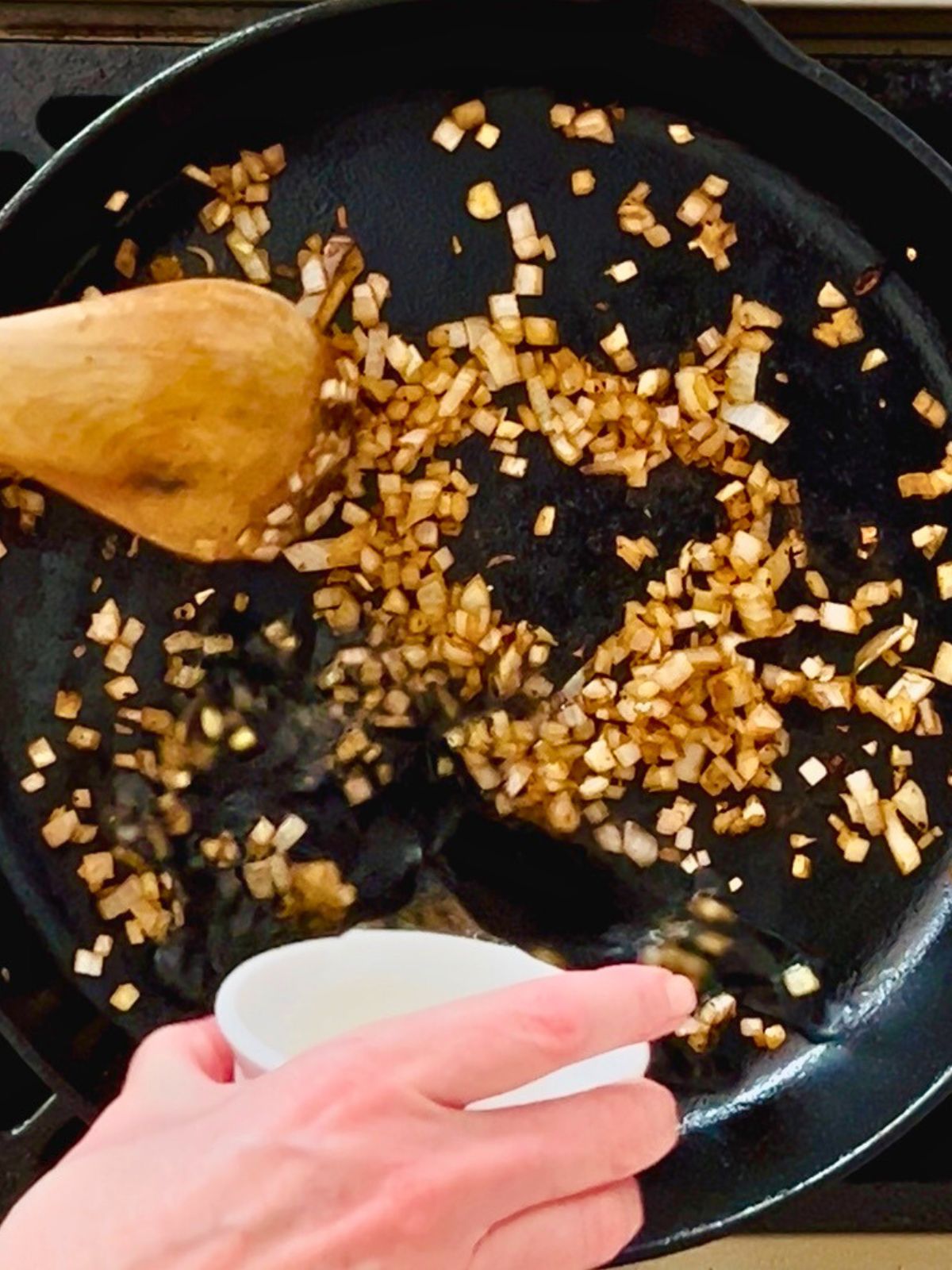 Wine is poured into a skillet of softened shallots to deglaze the brown bits.