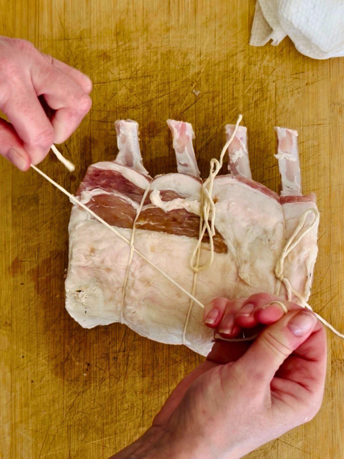 Butcher twine is tied between the bones of the pork rib roast.